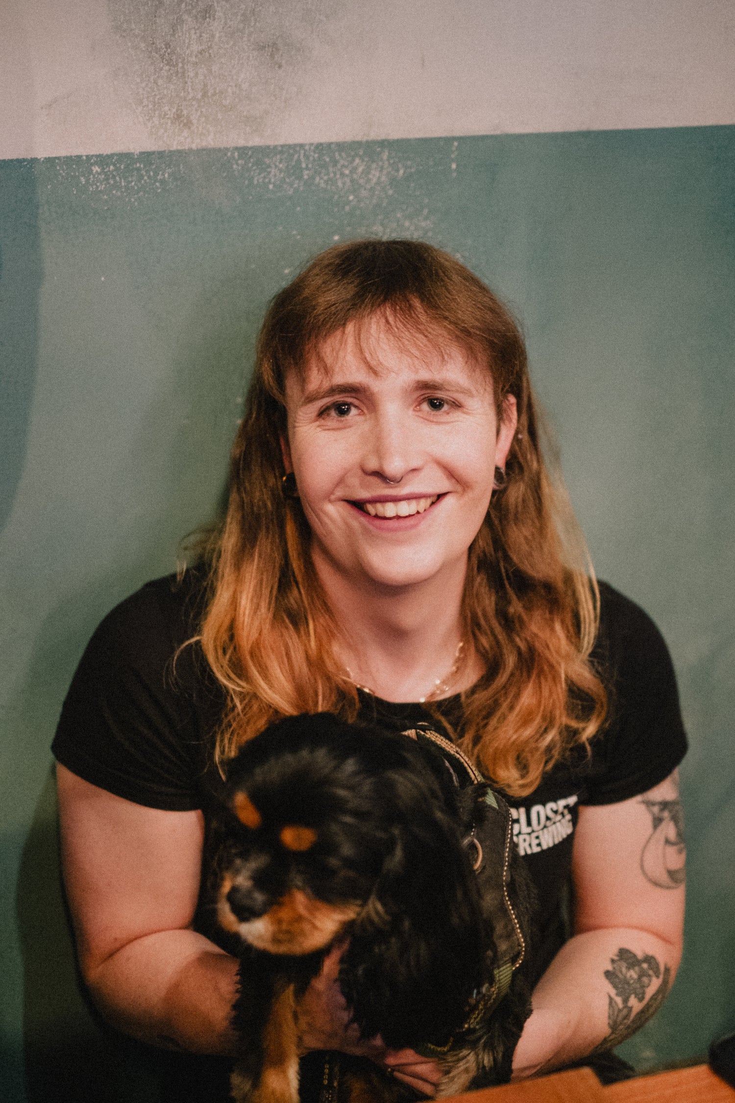 Person holding a small dog against a plain background